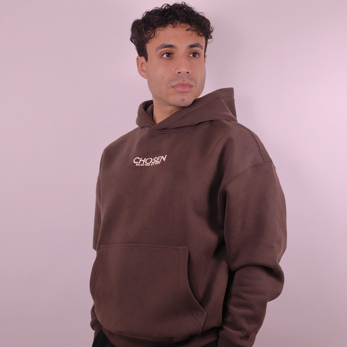 Man wearing a brown hoodie with Chosen text on a plain background