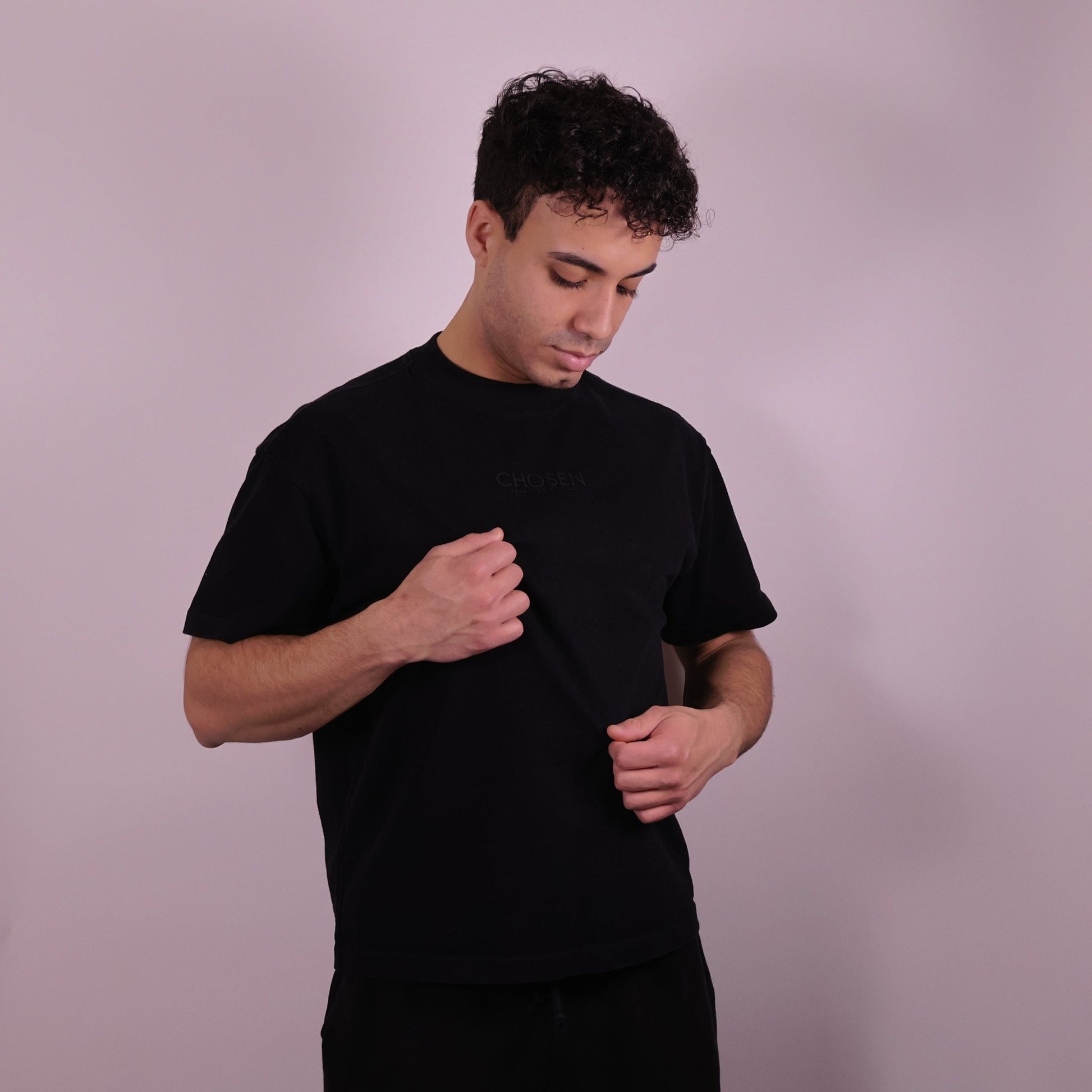 Close-up of ‘We Are His Masterpiece’ script on a black T-shirt by We Are Chosen Apparel