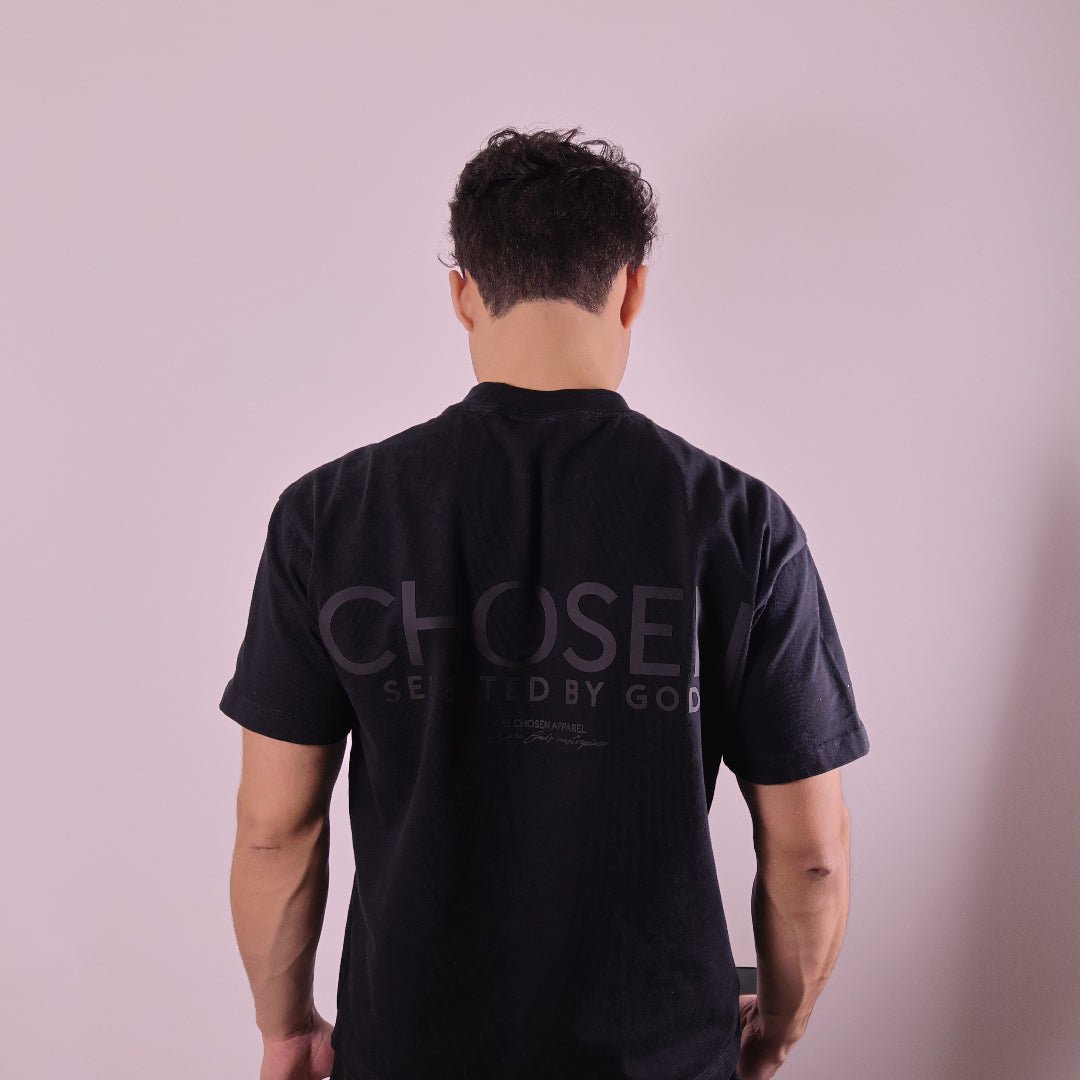 Close-up of ‘We Are His Masterpiece’ script on a black T-shirt by We Are Chosen Apparel