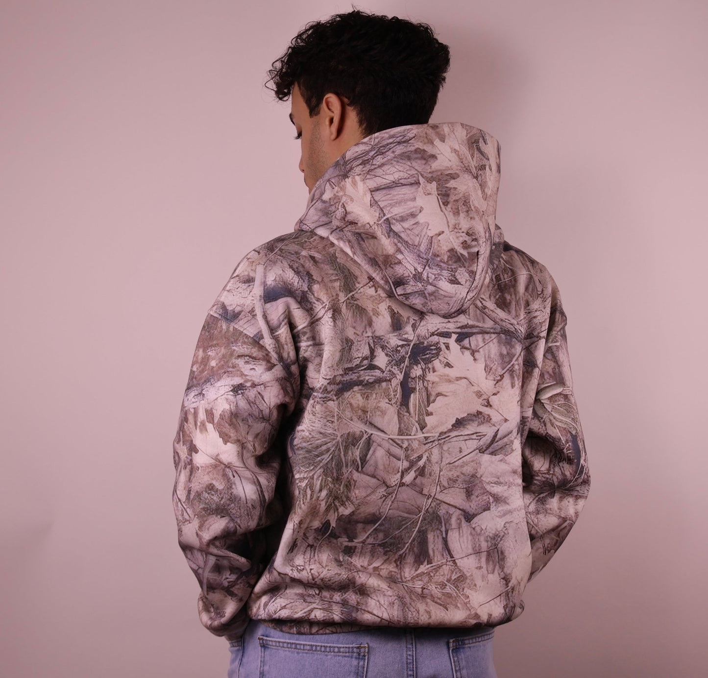 Person wearing a camouflage jacket against a plain background