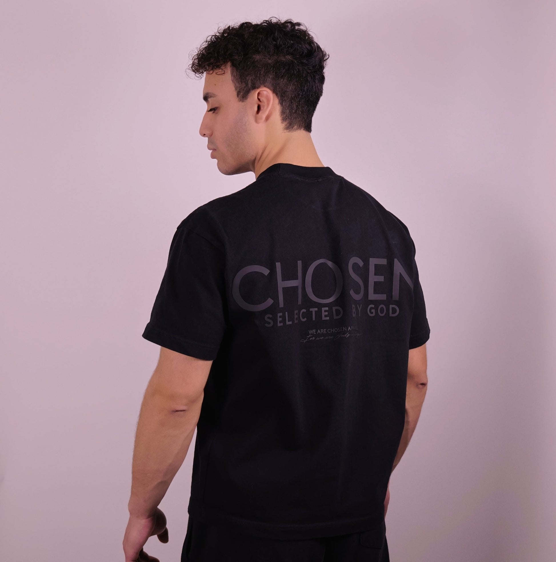 Close-up of ‘We Are His Masterpiece’ script on a black T-shirt by We Are Chosen Apparel