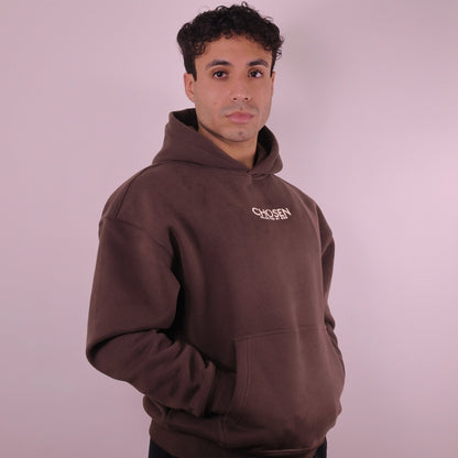 Man wearing a brown hoodie with Chosen text on a plain background