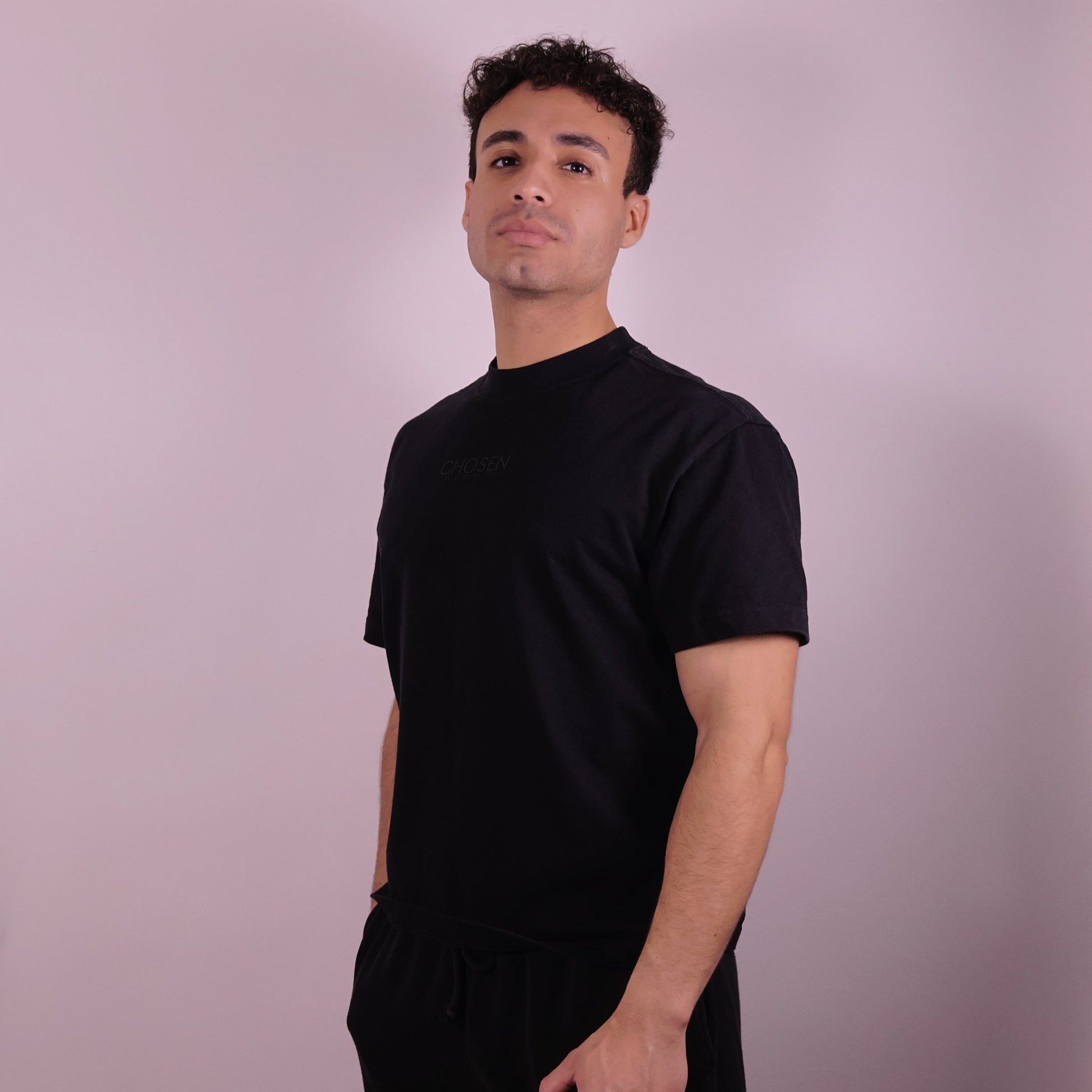 Close-up of ‘We Are His Masterpiece’ script on a black T-shirt by We Are Chosen Apparel